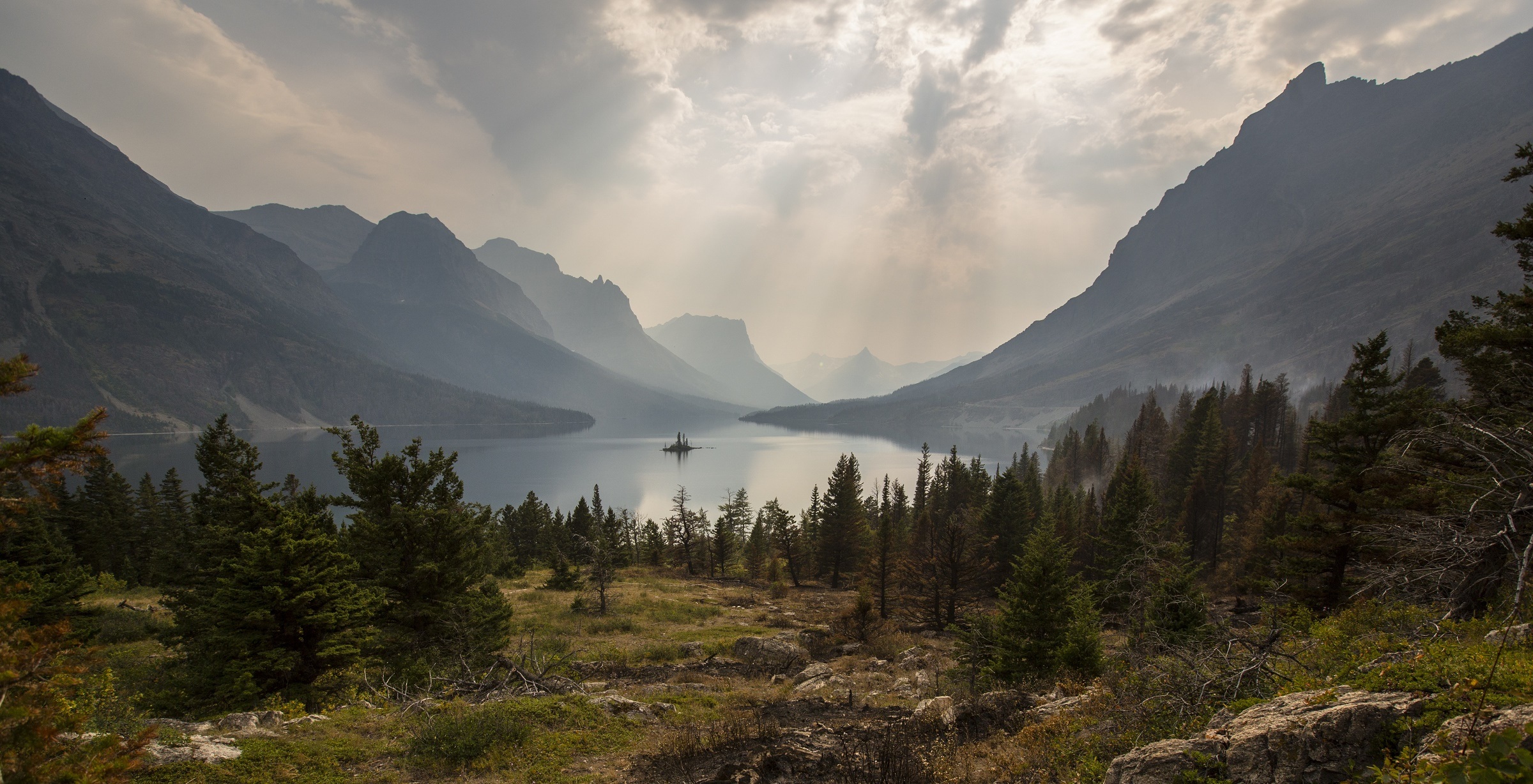 Lake in valley surrounded by forest and mountains